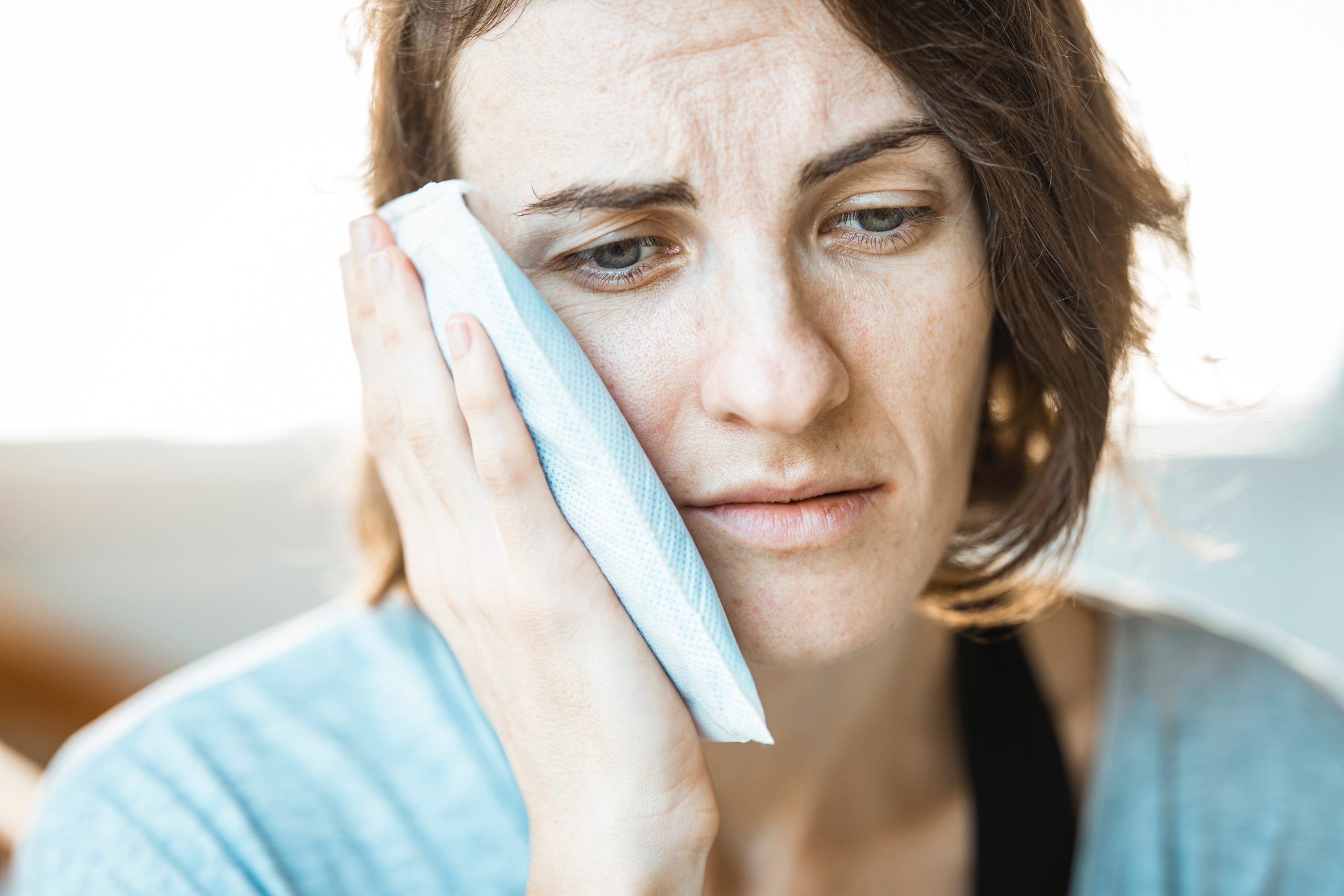 woman holding ice pack to her jaw from a toothache - cracked tooth treatment