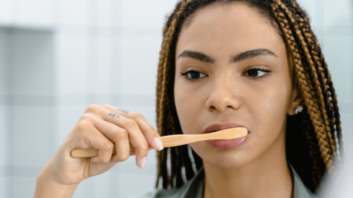 Why is Oral Hygiene Important? | Woman brushing her teeth in the mirror | Lake Pointe Dental Group in O'Fallon, IL